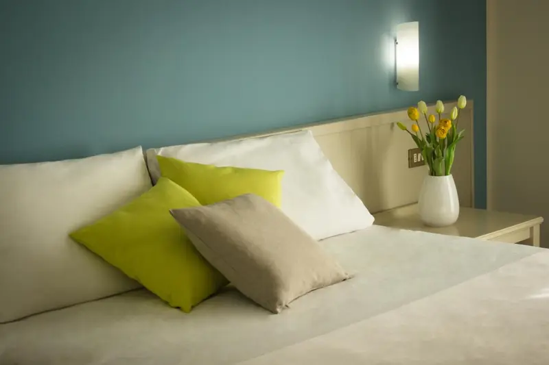 Un lit recouvert d'une couette blanche et de coussins colorés dans une chambre.