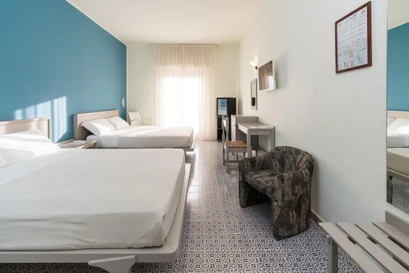 Chambre lumineuse avec deux lits et un coin salon.