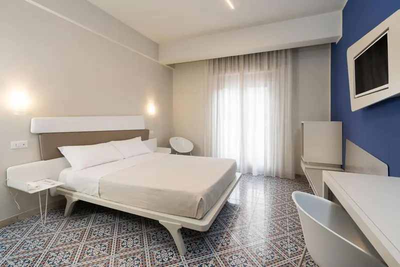 Une chambre lumineuse avec un grand lit et un bureau.