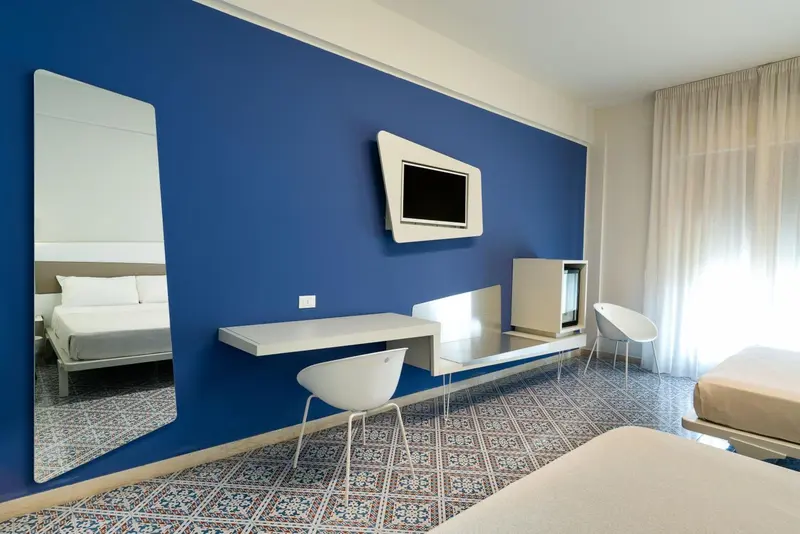 Une chambre moderne avec un mur bleu vif et un grand miroir.