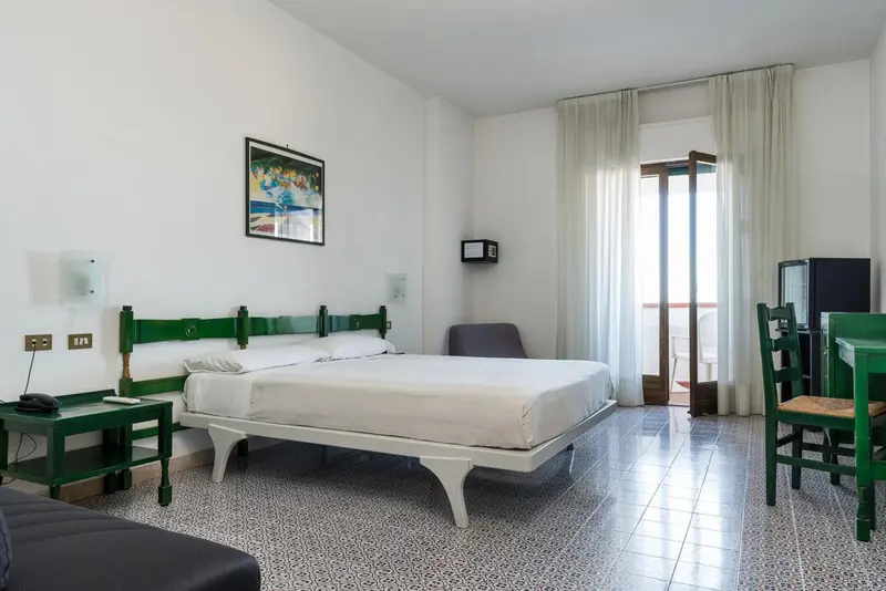Une chambre lumineuse avec un lit double et un accès à un balcon.