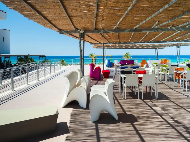 Terrasse aménagée avec mobilier blanc et coloré face à la mer.