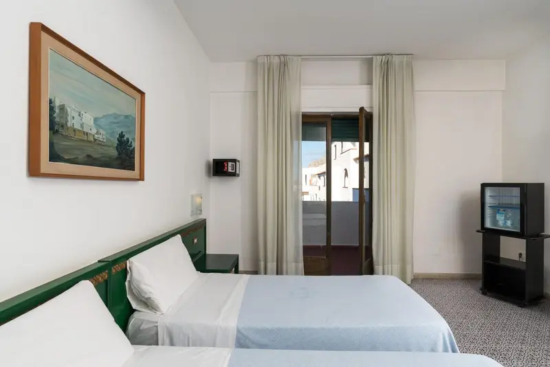 Une chambre lumineuse avec un lit simple et un accès à une terrasse.
