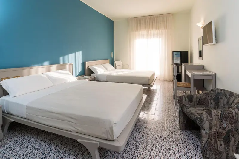 Une chambre lumineuse avec deux lits simples et un coin salon.