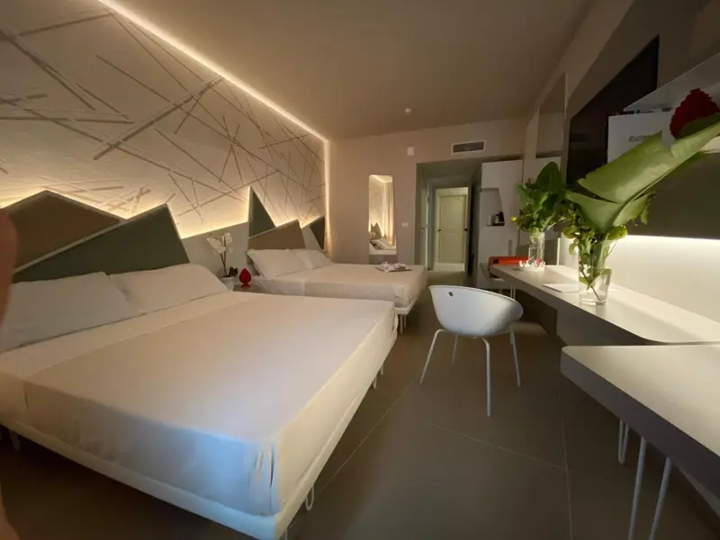 Chambre lumineuse avec deux lits et une décoration murale graphique.
