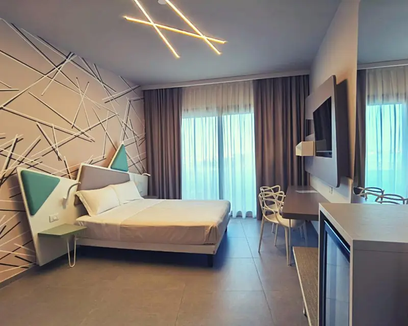 Une chambre lumineuse avec un grand lit et un bureau.