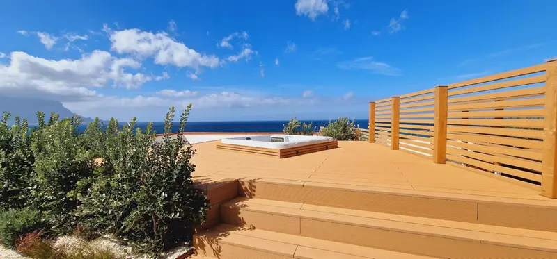 Jacuzzi sur une terrasse en bois avec vue sur la mer et les montagnes.