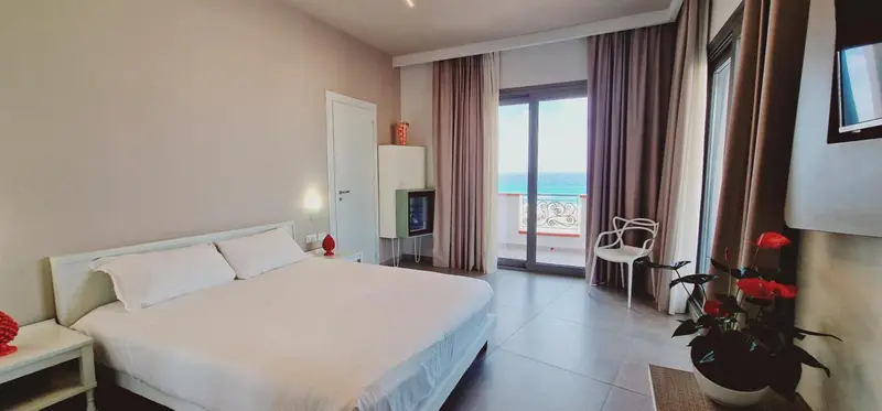 Une chambre lumineuse avec un grand lit et un accès à un balcon.