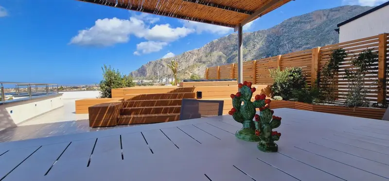 Terrasse en bois avec mobilier d'extérieur et vue sur les montagnes.