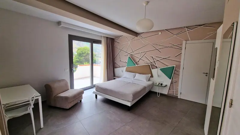 Une chambre lumineuse avec un lit double et un coin salon.