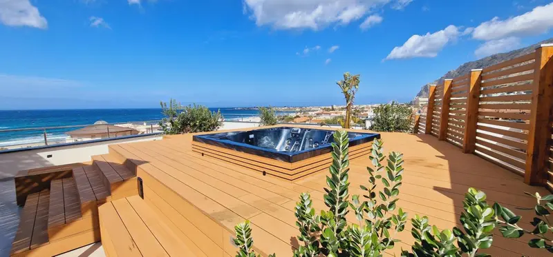 Terrasse en bois avec jacuzzi et vue sur la mer.