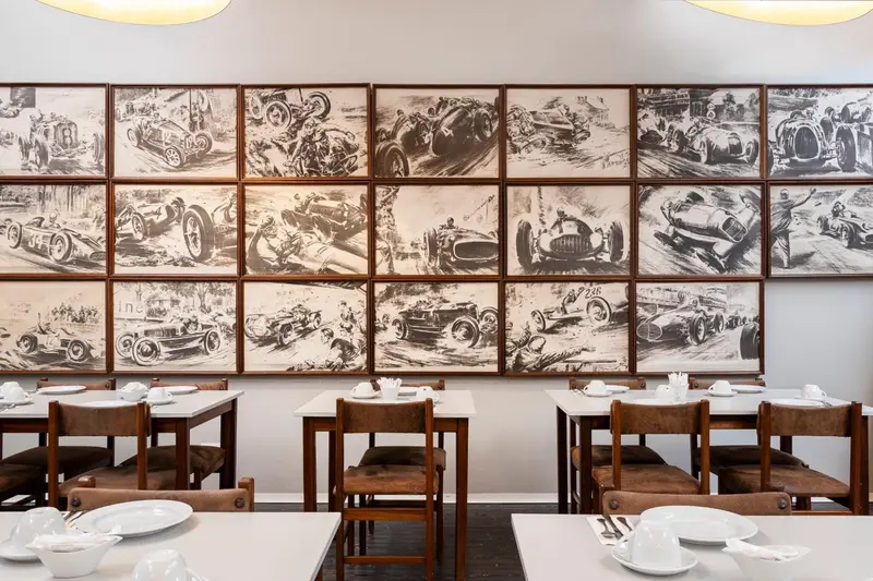 Une salle lumineuse avec des tables dressées devant un mur décoré de photographies en noir et blanc.