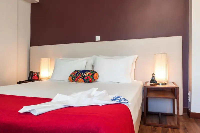 Un lit double avec une couverture rouge et des oreillers blancs dans une chambre.