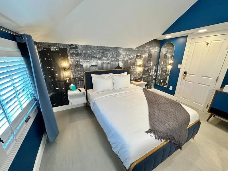 Une chambre avec un grand lit recouvert d'une couverture grise et de coussins blancs.