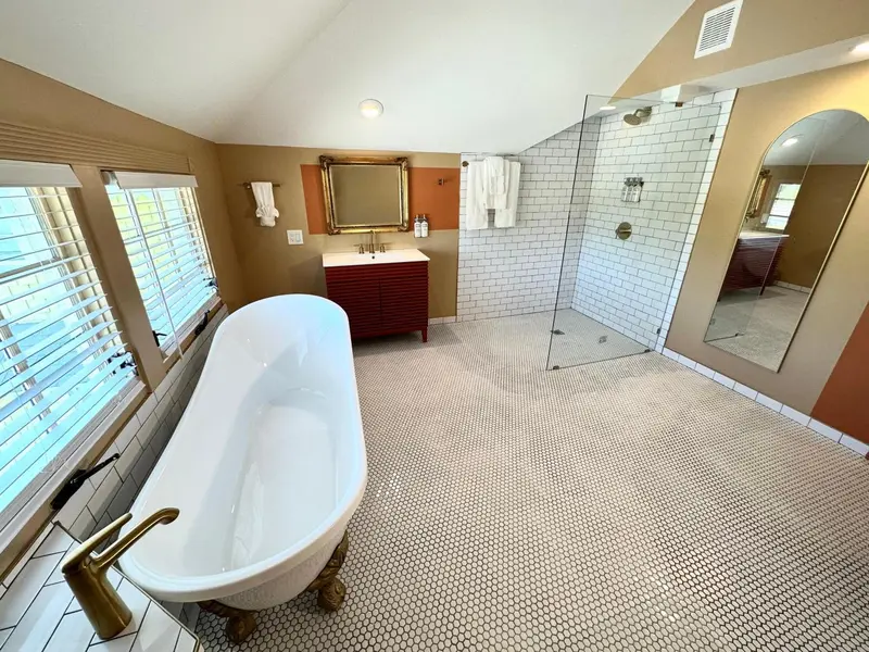 Une grande salle de bain lumineuse avec une baignoire et une douche à l'italienne.