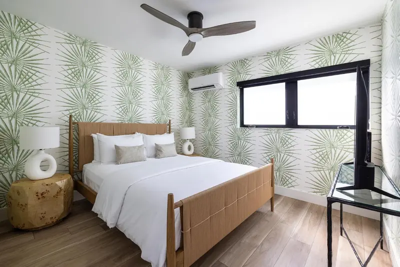 Une chambre lumineuse avec un lit double et un décor tropical.