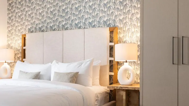 Un lit blanc avec des oreillers moelleux dans une chambre décorée de papier peint.