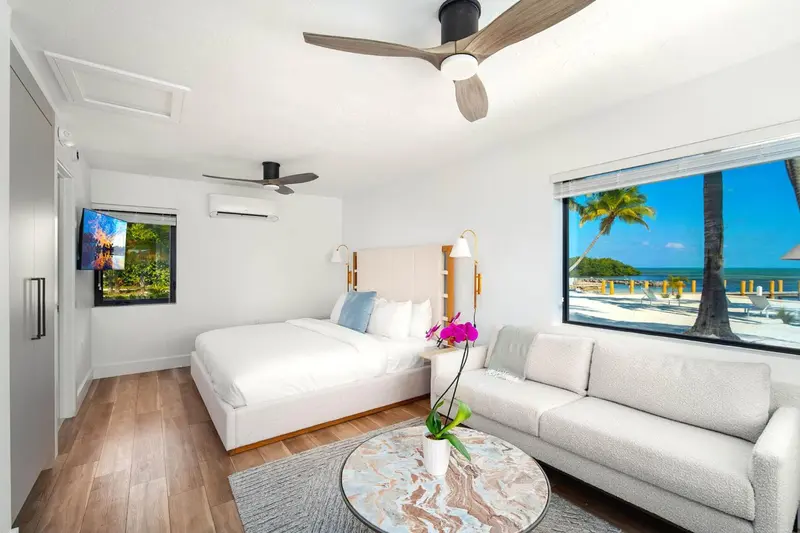 Une chambre lumineuse avec un lit et un canapé, donnant sur une plage.