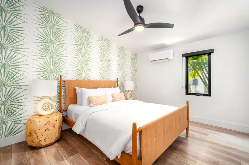 Une chambre lumineuse avec un lit double et un décor tropical.