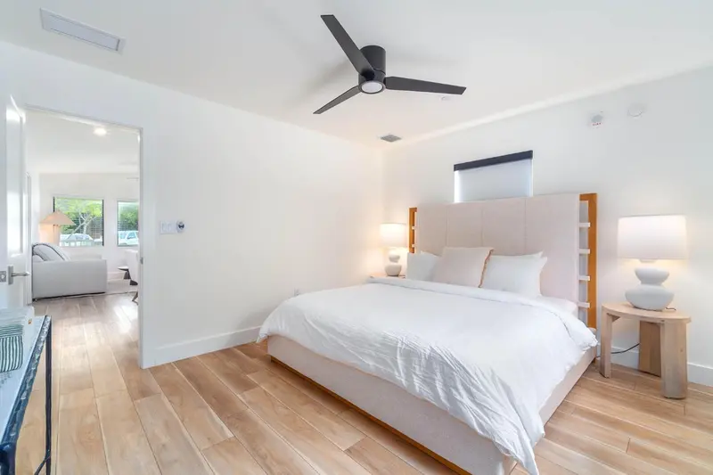Une chambre lumineuse avec un grand lit et un ventilateur de plafond.