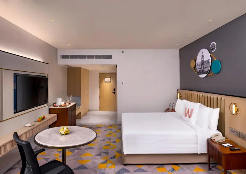 Chambre d'hôtel lumineuse avec un lit blanc et une décoration moderne.