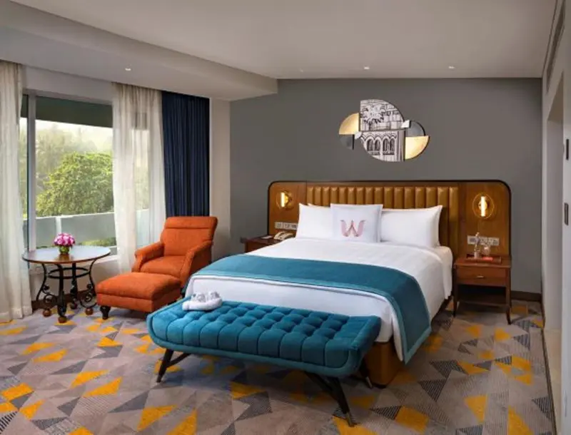 Une chambre d'hotel moderne avec un lit double et un fauteuil orange.