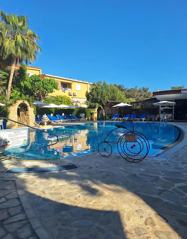 Une piscine rectangulaire avec des transats et des parasols, entourée d'une terrasse ensoleillée.