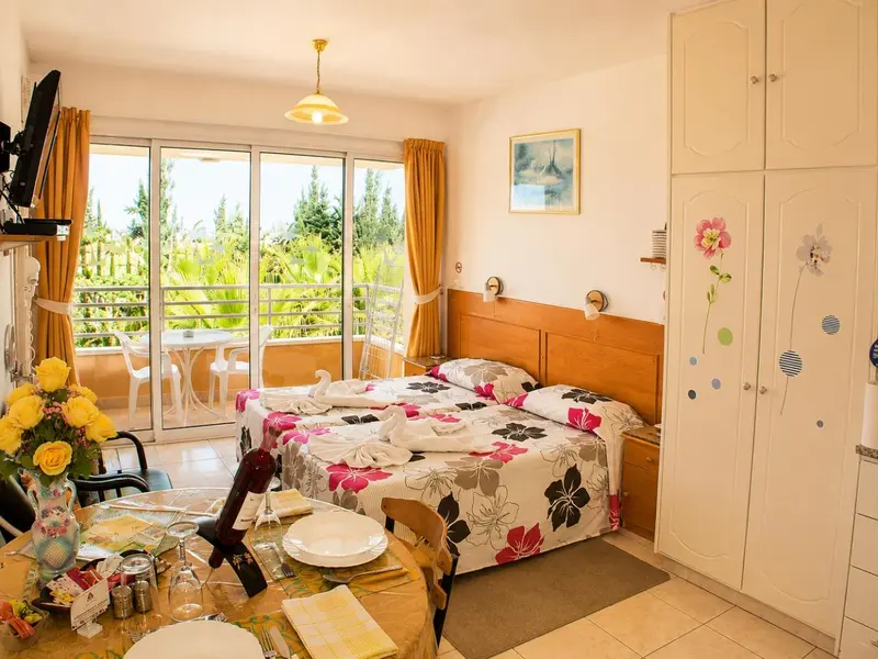 Une chambre lumineuse avec un lit double et un balcon fleuri.