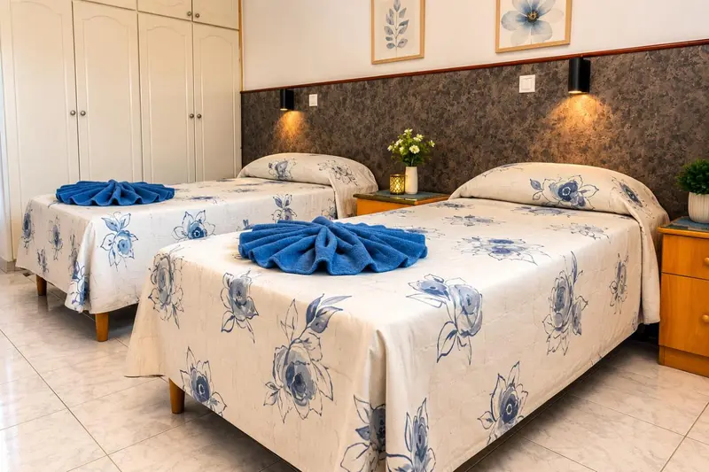 Deux lits simples décorés de motifs floraux dans une chambre lumineuse.