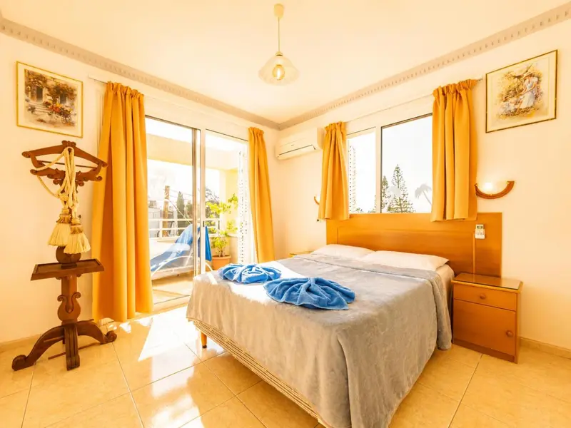 Chambre lumineuse avec un grand lit et un accès à une terrasse.