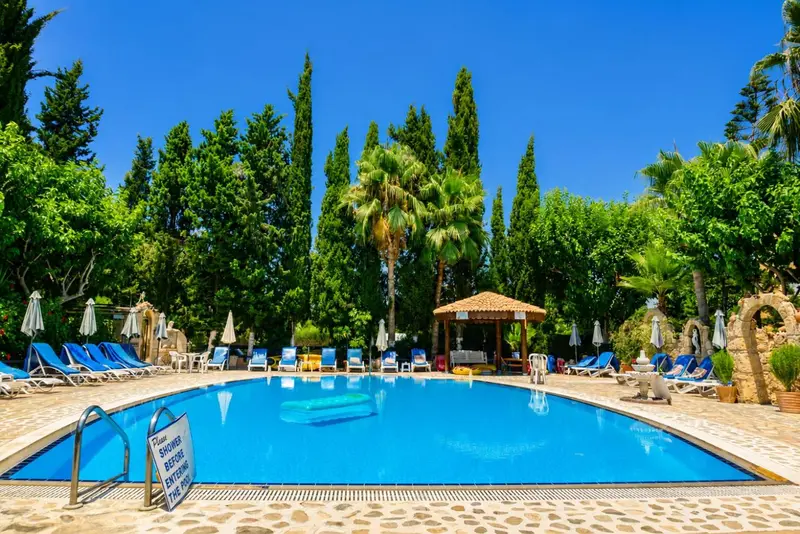Une piscine rectangulaire bordée de transats et de parasols, entourée d'une végétation luxuriante.