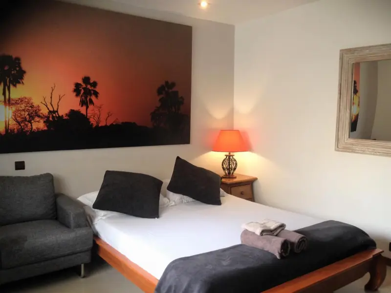 Une chambre lumineuse avec un lit et un fauteuil.