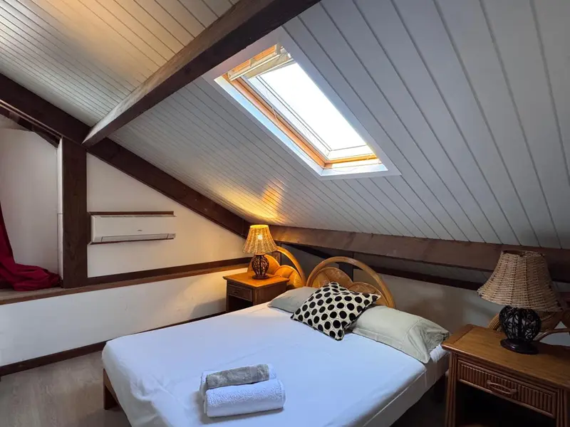 Une chambre mansardée lumineuse avec un lit simple et des meubles en bois.