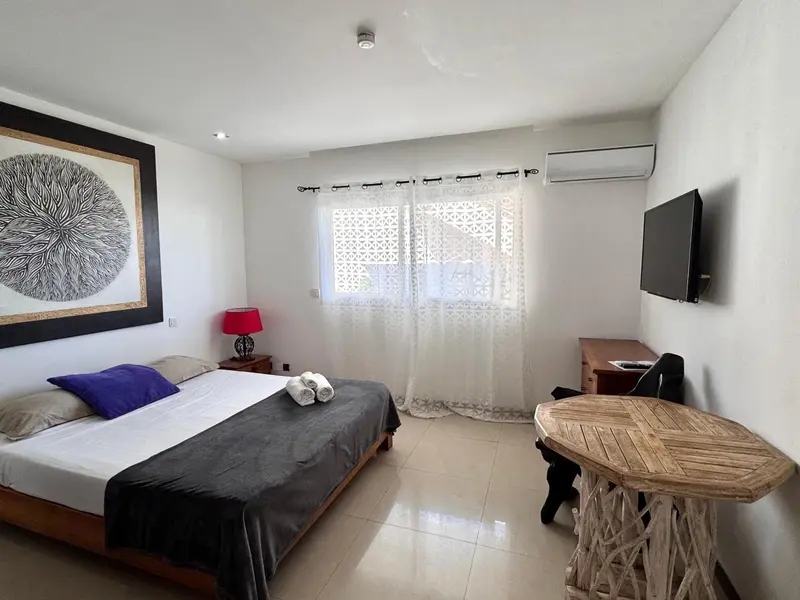 Une chambre lumineuse avec un grand lit et un bureau en bois.