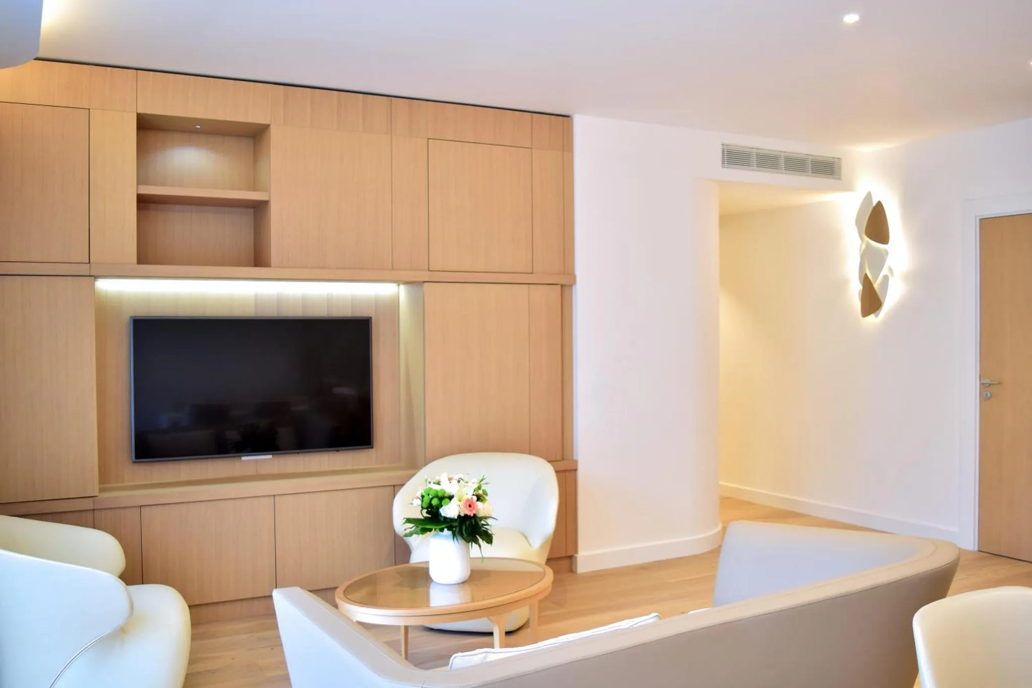 Espace de détente lumineux avec canapés et télévision intégrée.