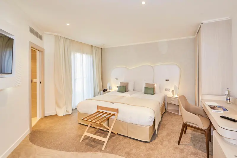Une chambre lumineuse avec un grand lit et un bureau.