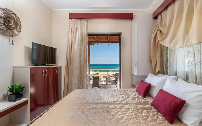 Une chambre lumineuse avec un lit et une vue sur la mer depuis une terrasse.