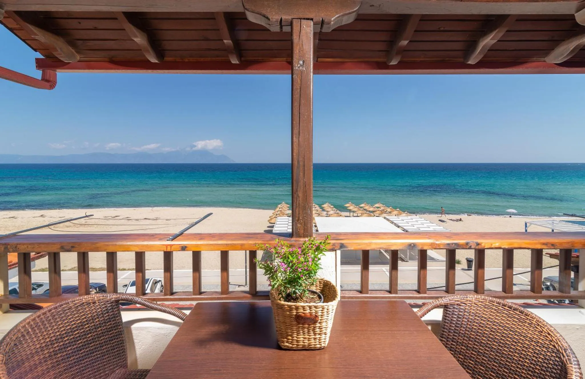 Vue sur la mer depuis une terrasse ombragée avec une table et des chaises.