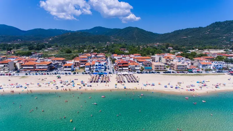 Vue aérienne d'une plage ensoleillée avec des transats et des baigneurs.
