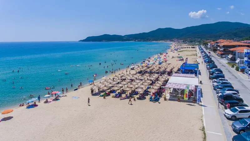 Vue aérienne d'une plage ensoleillée avec parasols et personnes se baignant.