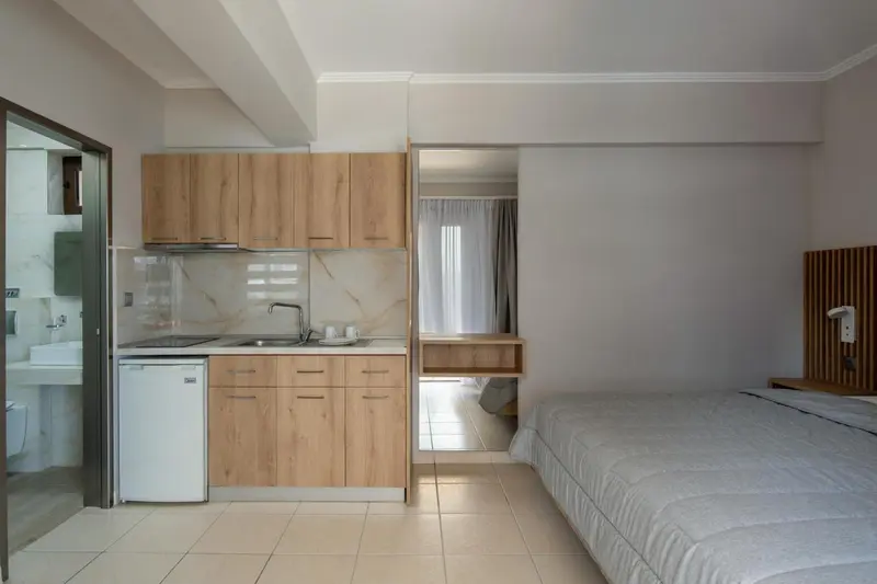 Une kitchenette moderne s'ouvre sur une chambre avec un lit simple.