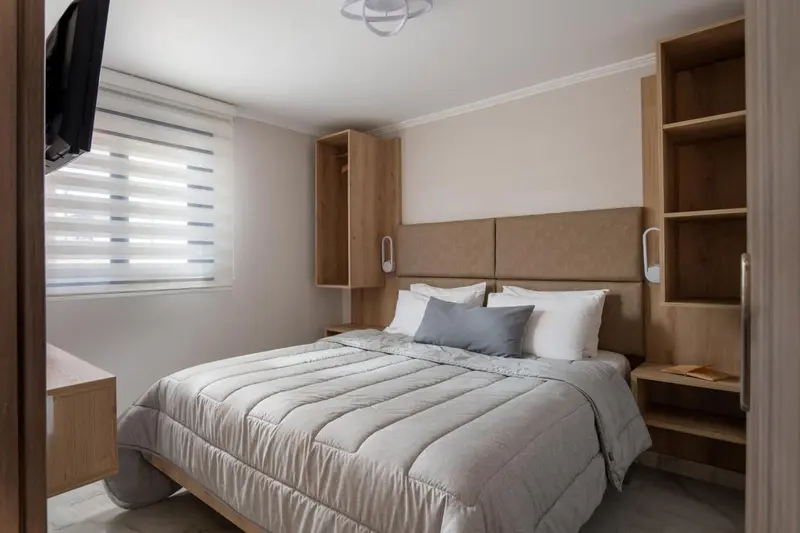Une chambre lumineuse avec un grand lit et des rangements intégrés.