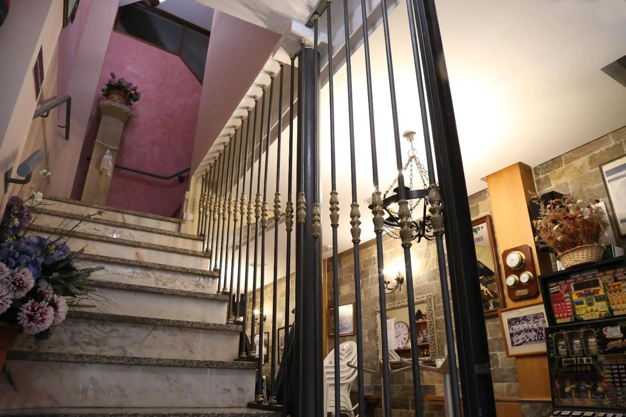 Escalier en pierre avec rampe en fer forgé et décoration florale.