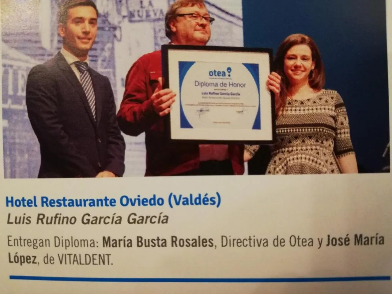 Trois personnes sourient en tenant un diplôme dans un intérieur décoré.