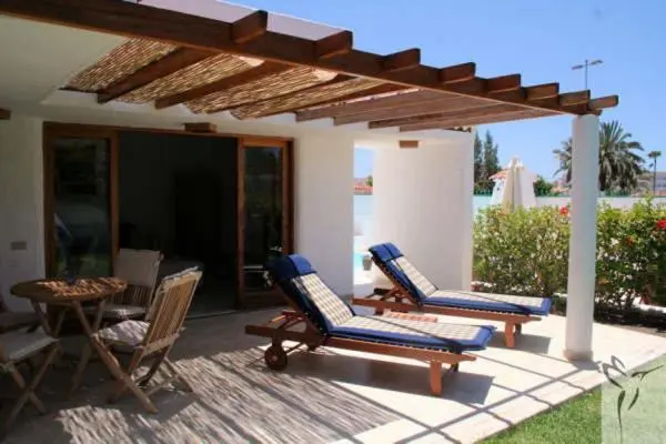 Terrasse ombragée avec mobilier de jardin et accès à un logement.