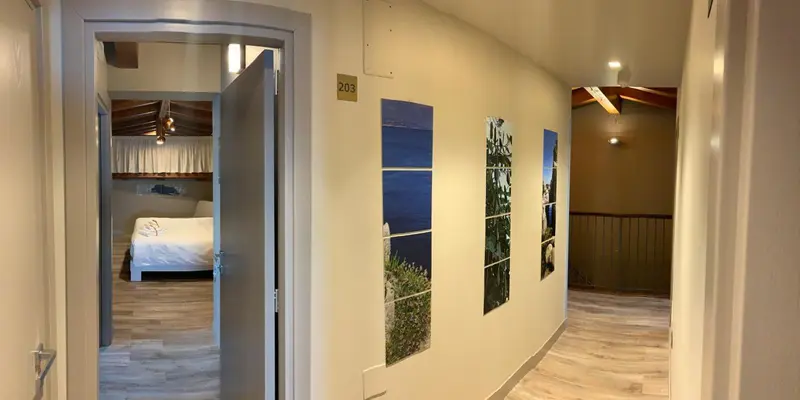 Couloir d'hôtel avec des portes ouvertes sur des chambres décorées.