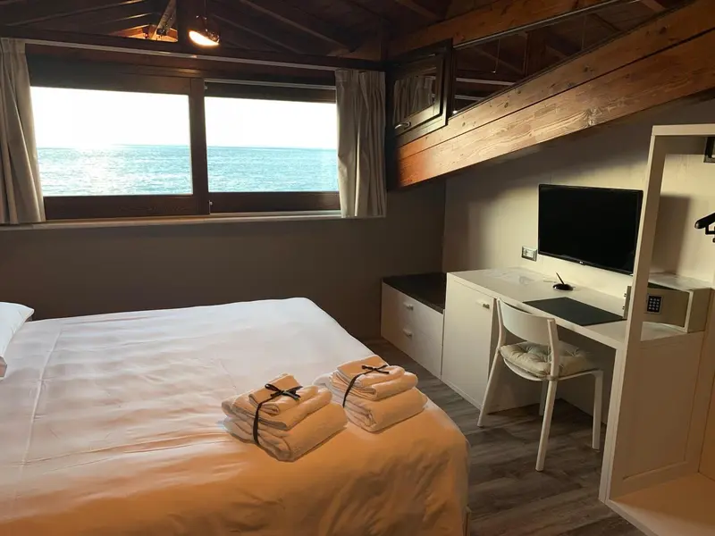 Une chambre lumineuse avec un lit et un espace bureau donnant sur la mer.