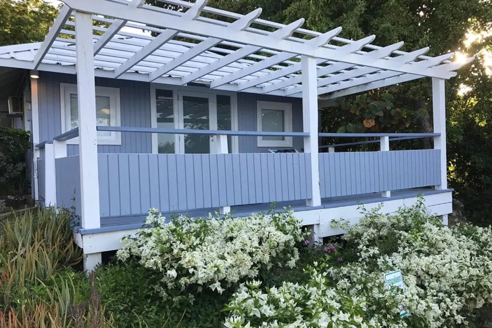 Terrasse ombragée devant un bâtiment bleu clair.