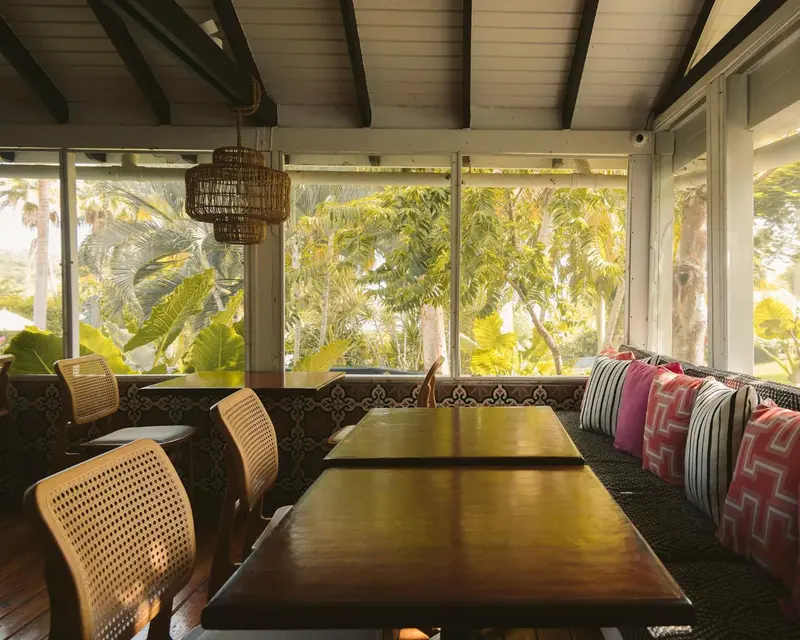 Une salle à manger lumineuse s'ouvre sur une végétation luxuriante.