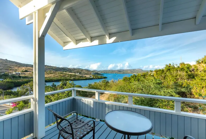 Terrasse avec vue sur une colline verdoyante et la mer.